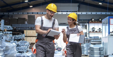 Twee magazijnmedewerkers met veiligheidshelmen bespreken voorraad
